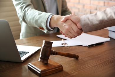 Photo of Notary and client shaking hands in office, closeup. Law and justice concept