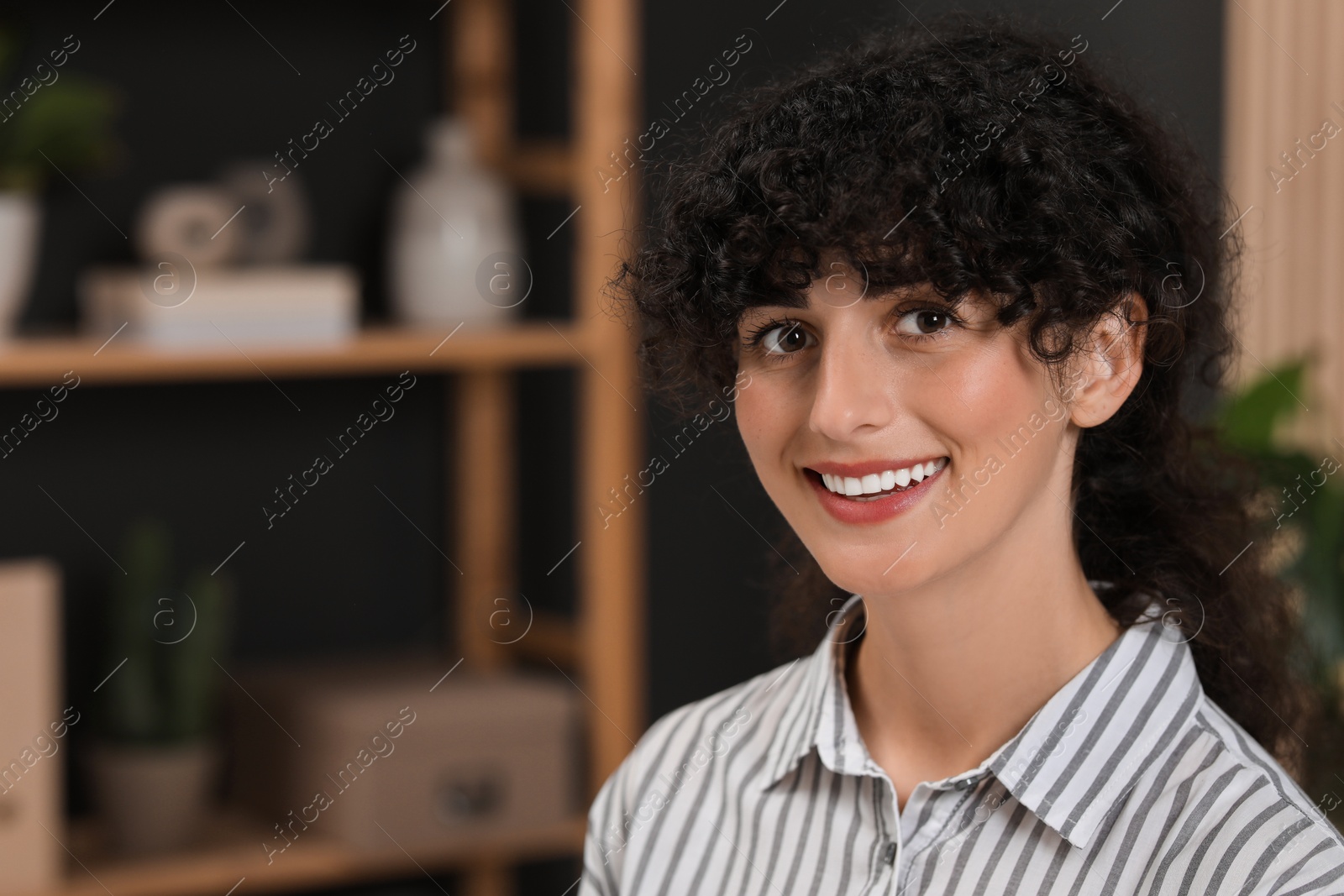 Photo of Portrait of beautiful woman with curly hair indoors. Attractive lady smiling and looking into camera. Space for text