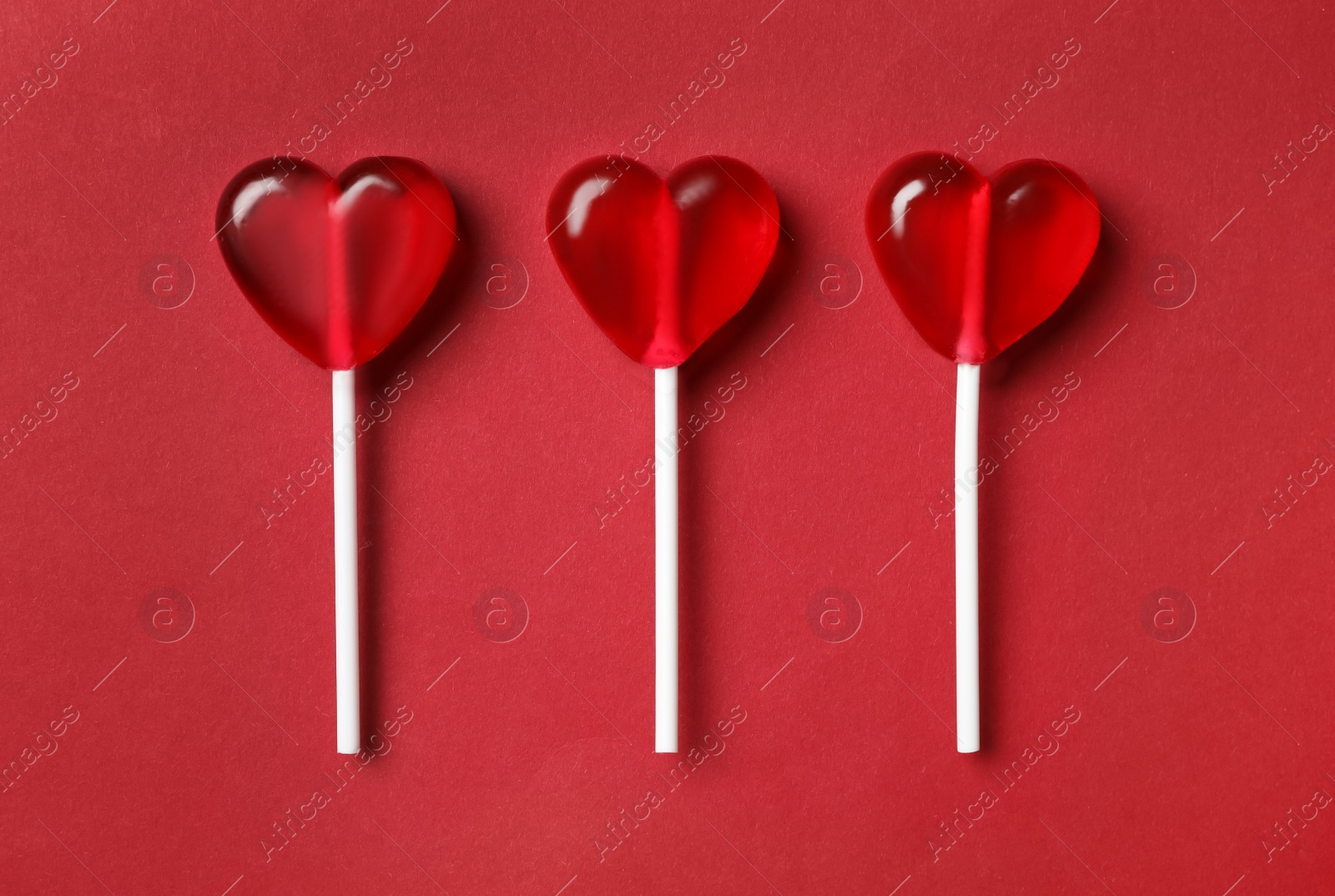 Photo of Sweet heart shaped lollipops on red background, flat lay. Valentine's day celebration