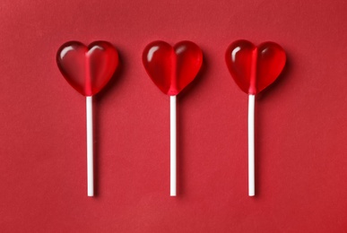Photo of Sweet heart shaped lollipops on red background, flat lay. Valentine's day celebration