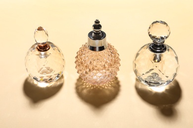 Photo of Different elegant perfume bottles on beige background