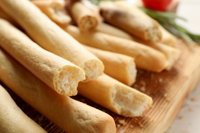 Delicious grissini sticks on wooden board, closeup