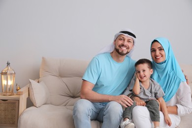 Photo of Happy Muslim family on sofa in living room, space for text