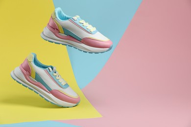 Photo of Stylish presentation of bright sneakers on color background, space for text