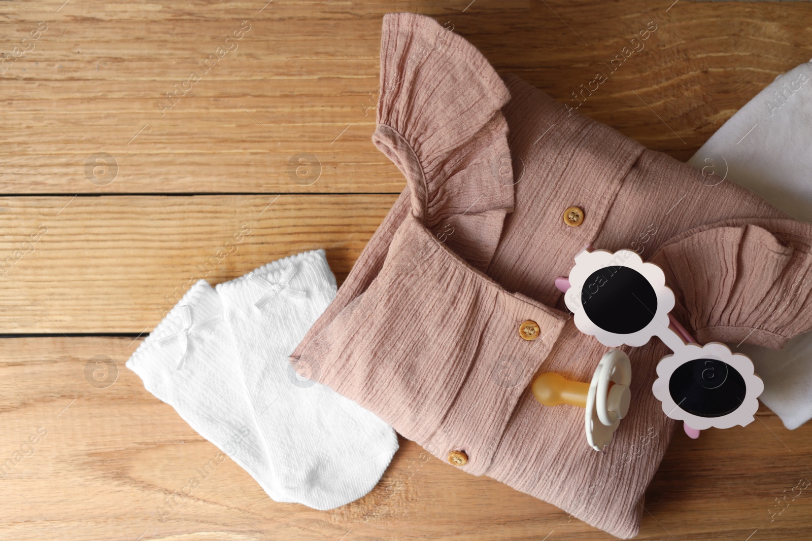 Photo of Stylish child clothes and accessories on wooden background, flat lay