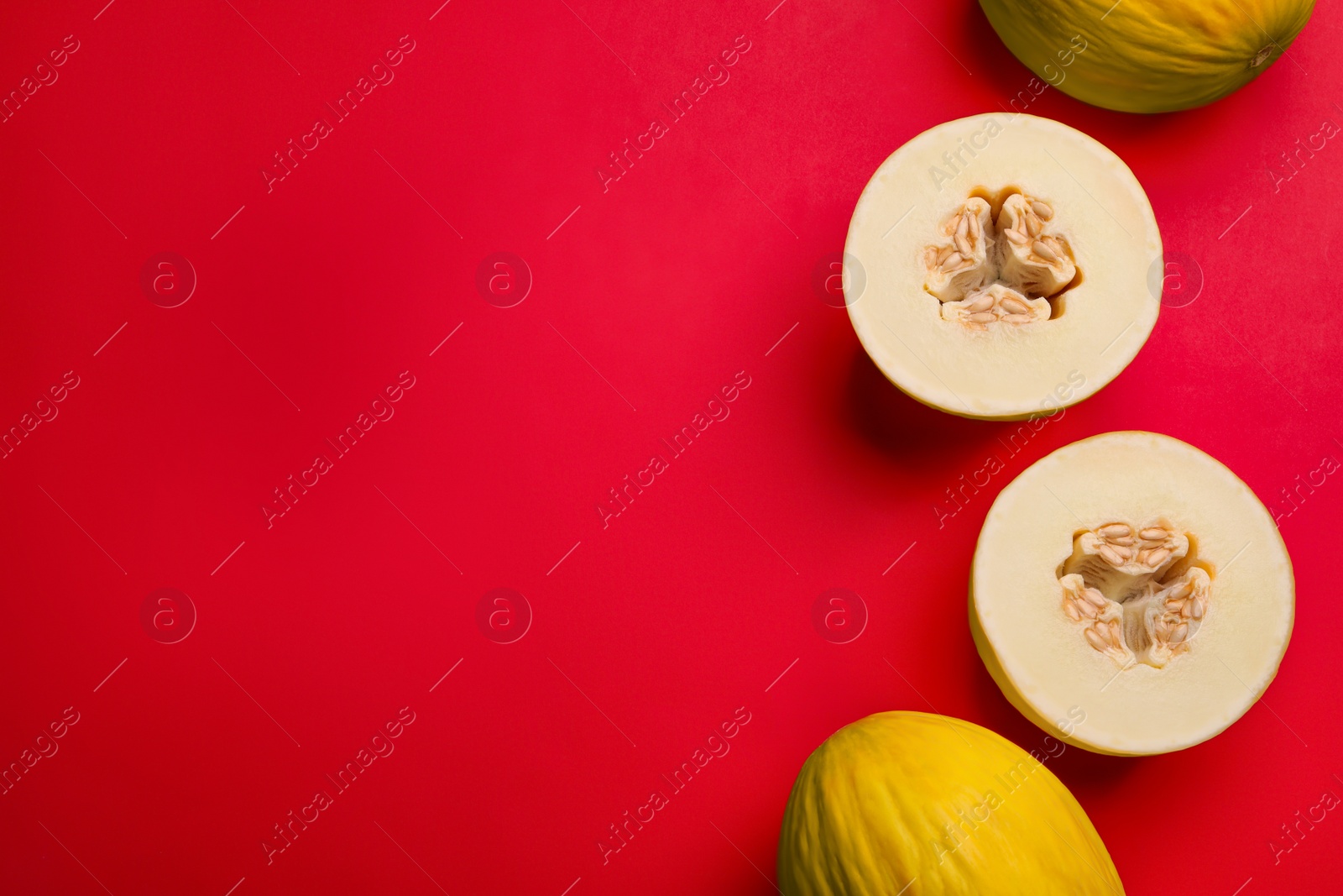 Photo of Ripe tasty melons on red background, flat lay. Space for text