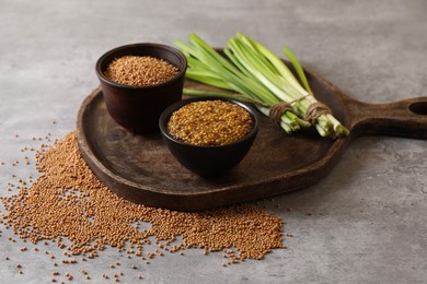 Photo of Serving board with delicious whole grain mustard, seeds and fresh green onion on grey table
