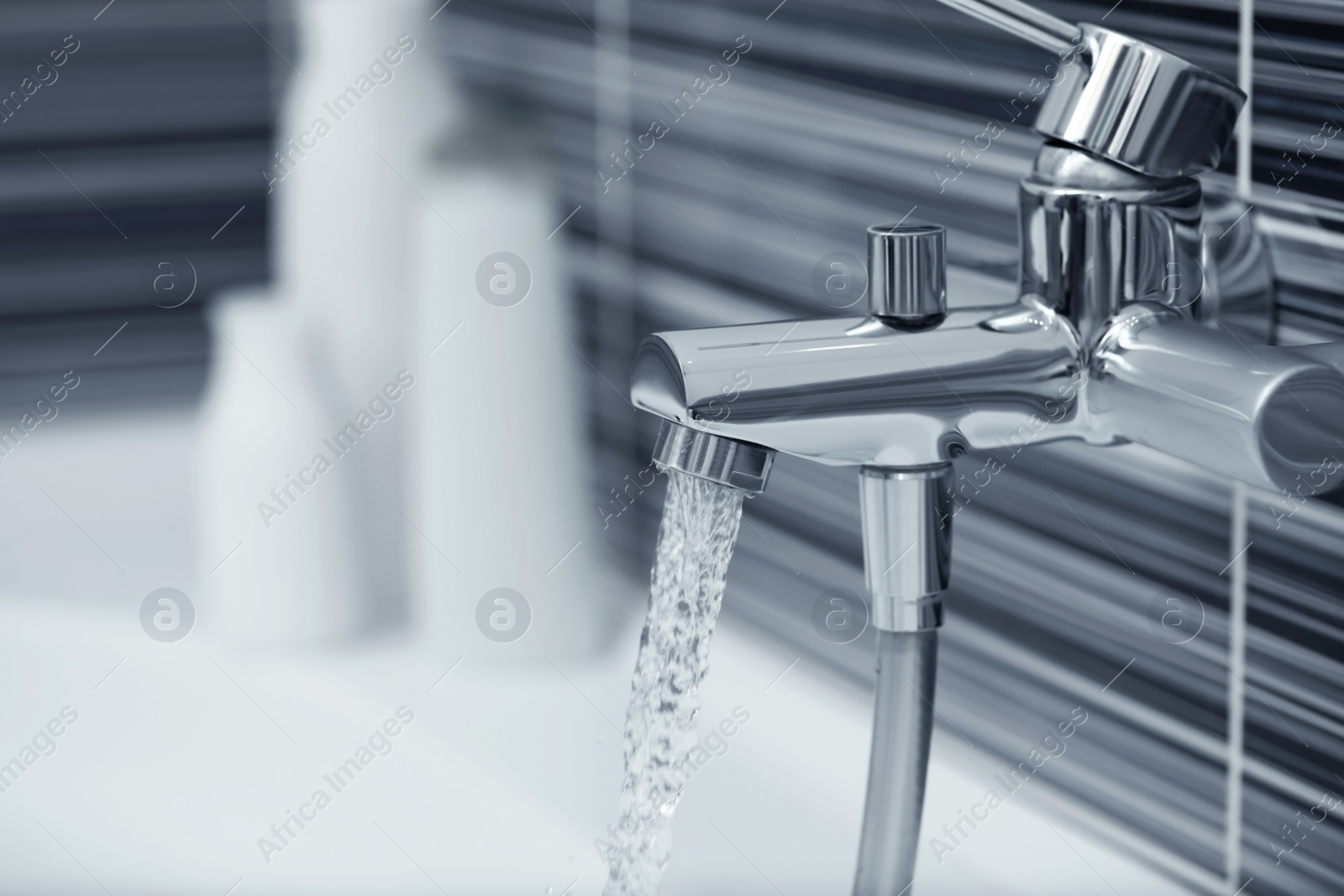 Photo of Water flowing from bath tap installed on black and white wall