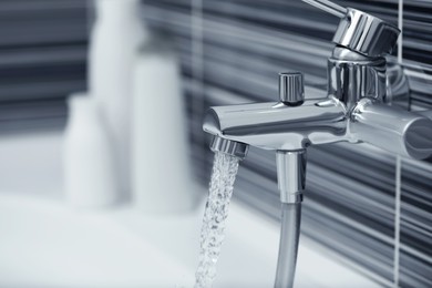 Photo of Water flowing from bath tap installed on black and white wall