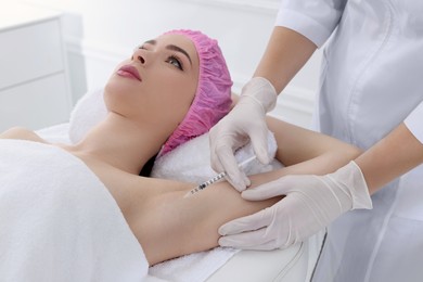 Cosmetologist injecting young woman's armpit in clinic. Treatment of hyperhidrosis