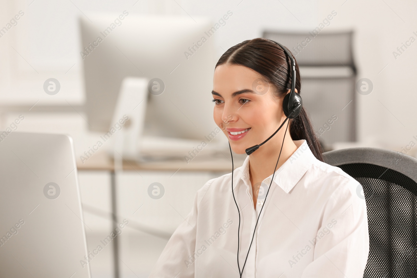 Photo of Hotline operator with headset working on computer in office