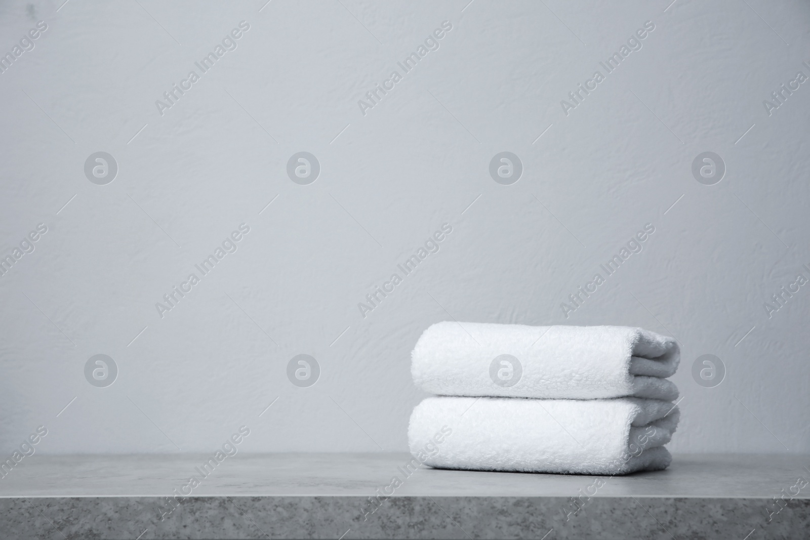 Photo of Stack of towels on table against grey background