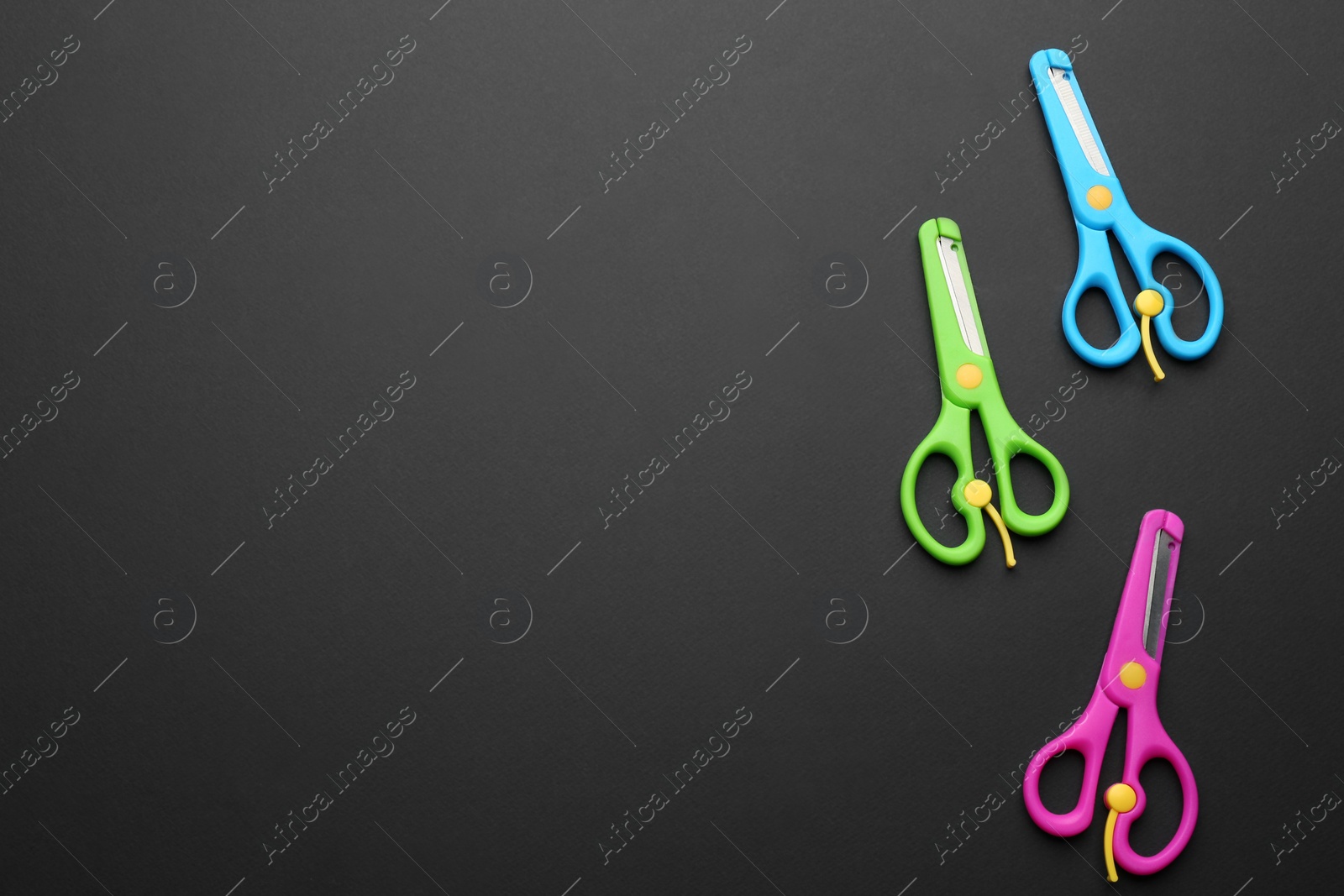 Photo of Set of training scissors on dark background, flat lay. Space for text