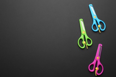 Photo of Set of training scissors on dark background, flat lay. Space for text