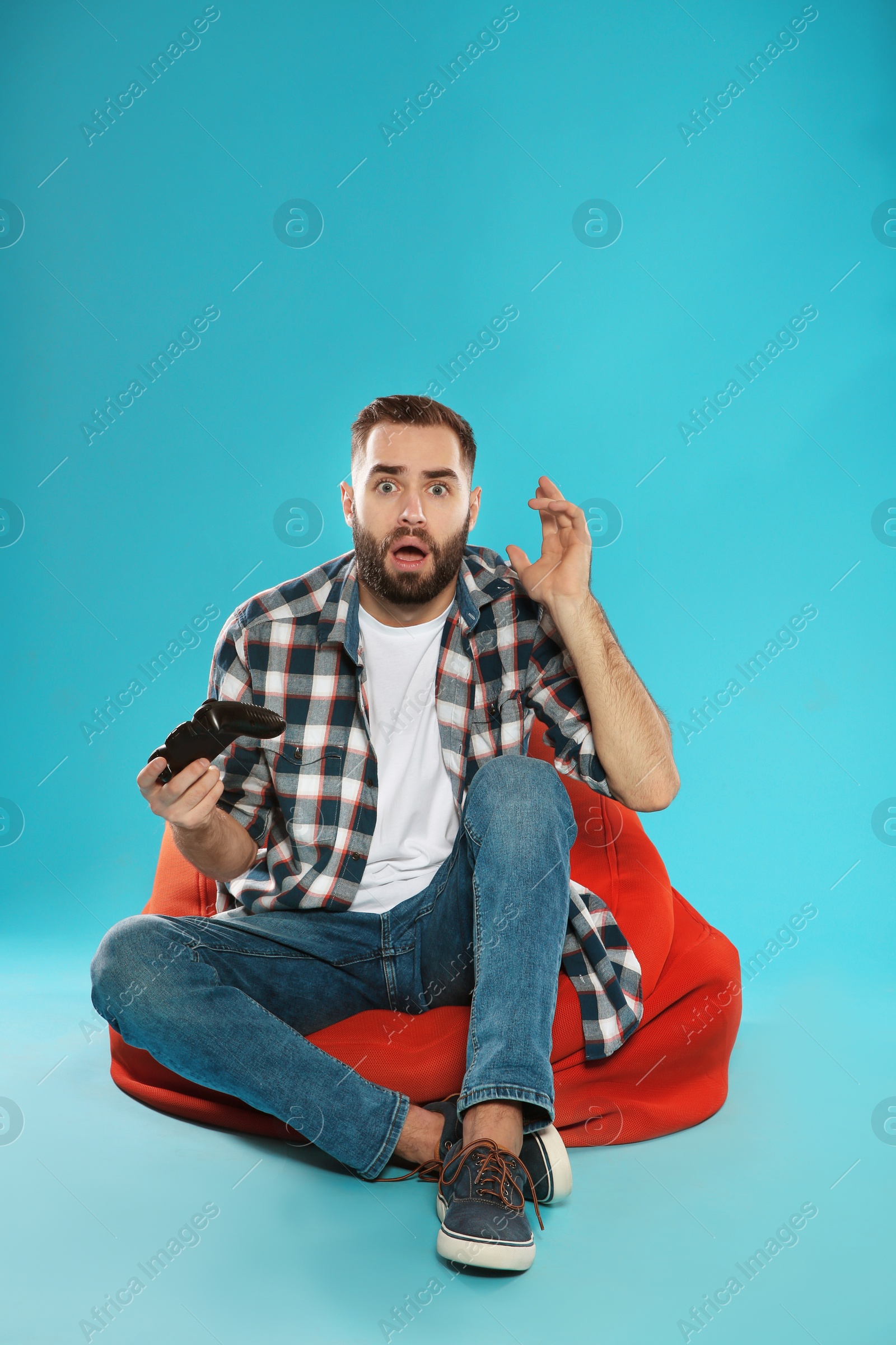 Photo of Emotional young man playing video games with controller on color background. Space for text