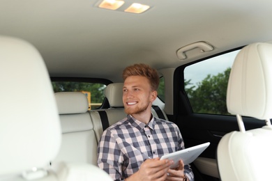 Photo of Attractive young man with tablet in luxury car