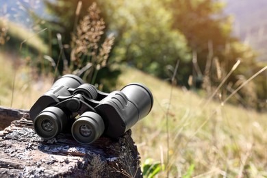 Photo of Modern binoculars on wooden surface outdoors, space for text