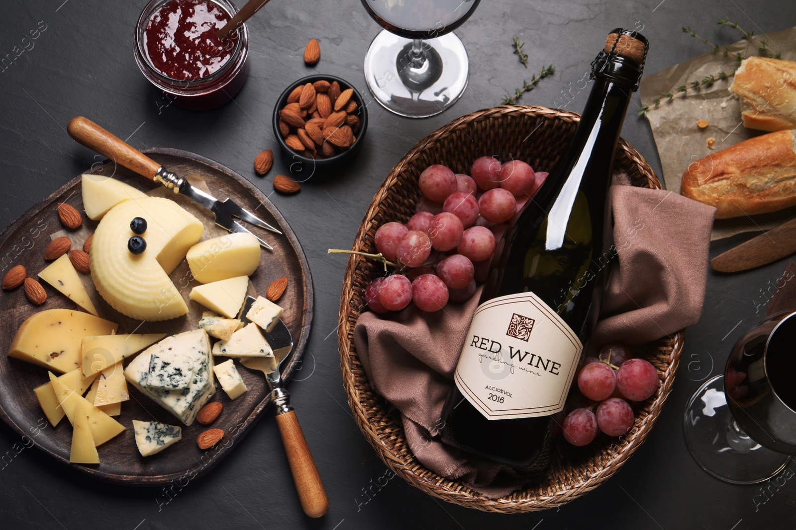 Photo of Flat lay composition with bottle of red wine and snacks on black table