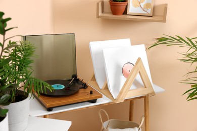 Photo of Stylish turntable with vinyl record on wooden table in room
