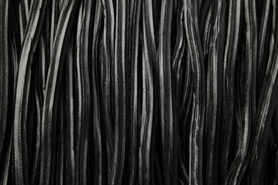 Photo of Tasty black liquorice candies as background, top view
