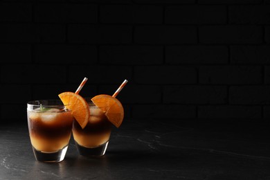 Photo of Tasty refreshing drink with coffee and orange juice on grey table against dark background, space for text