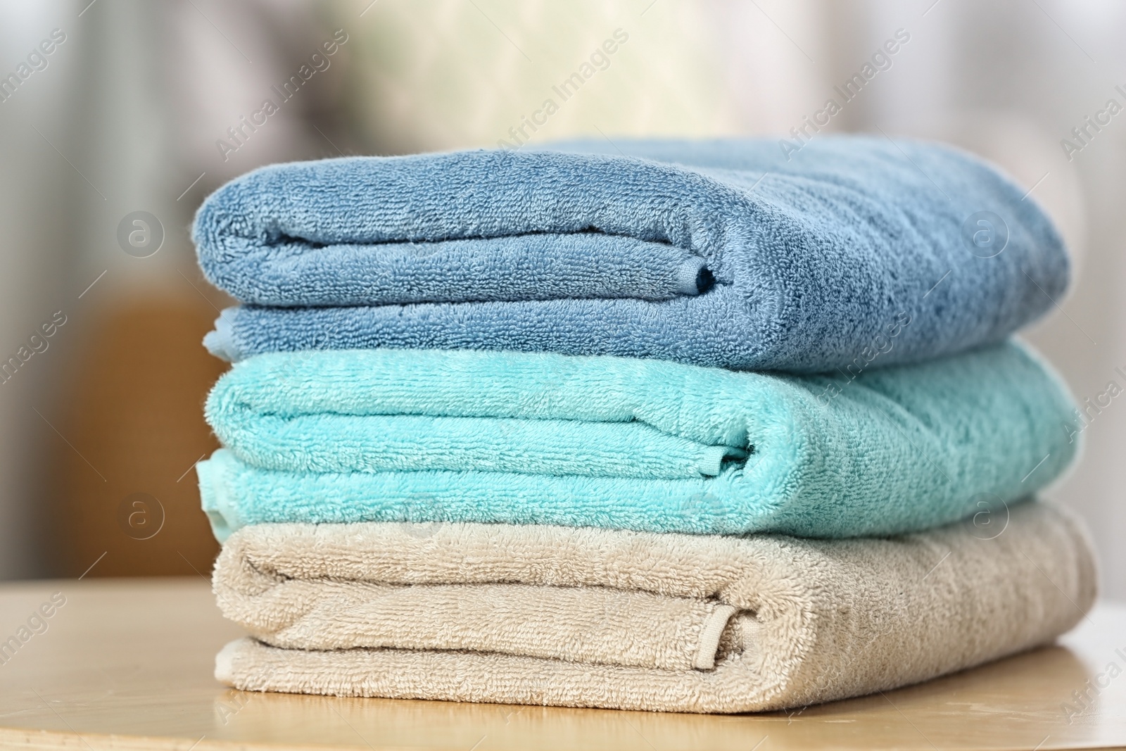 Photo of Stack of folded clean soft towels on table indoors, closeup