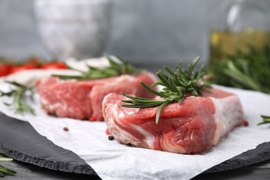 Fresh raw meat with rosemary on slate plate, closeup