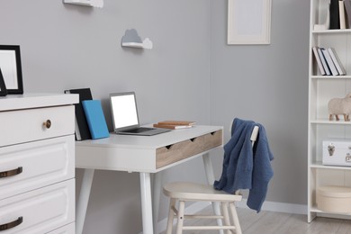 Photo of Stylish workplace with laptop on white desk. Home office interior