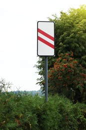 Photo of Road sign Countdown Beacon to Railway Crossing near plants outdoors