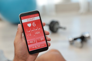 Photo of Man using fitness app on smartphone indoors, closeup. Space for text