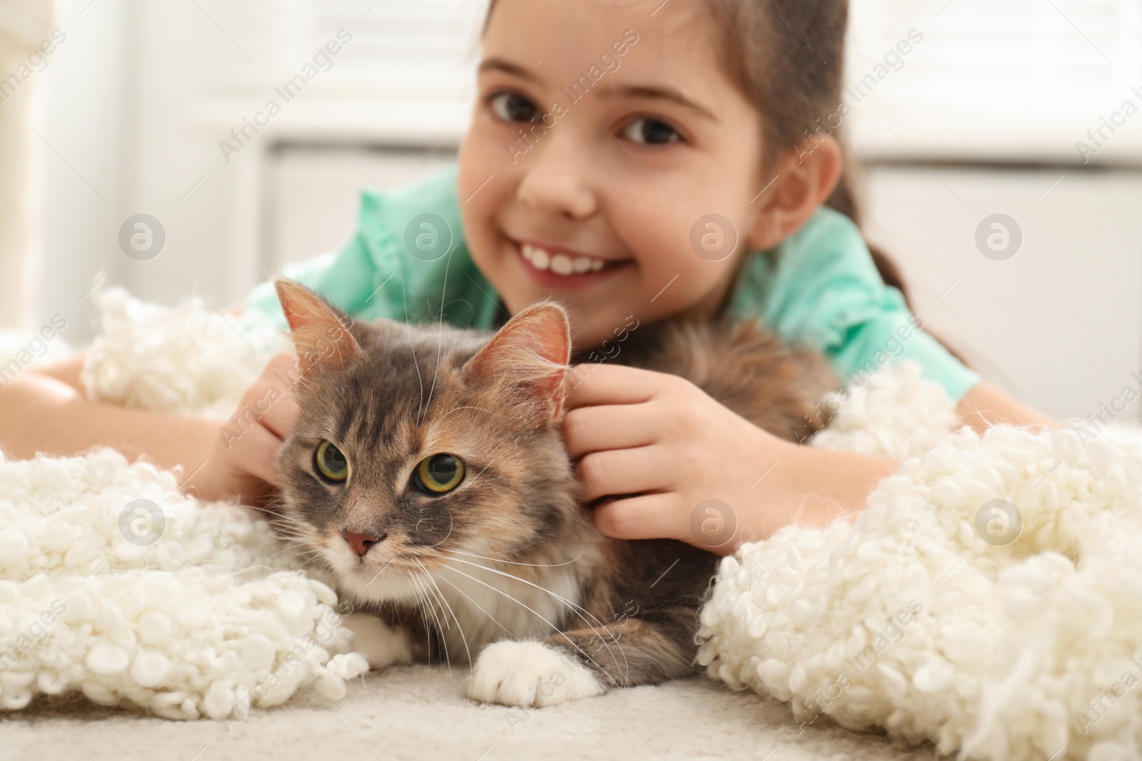 Photo of Cute little girl with cat lying on carpet at home. First pet