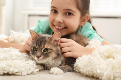 Photo of Cute little girl with cat lying on carpet at home. First pet