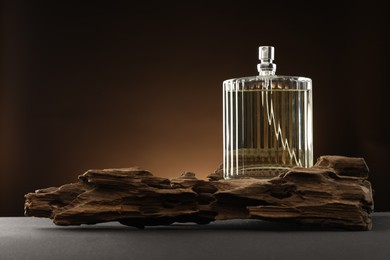 Photo of Luxury men`s perfume in bottle on grey table against brown background, space for text