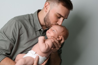 Photo of Father with his newborn son on light grey background