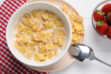 Photo of Bowl of tasty corn flakes and strawberries served for breakfast on white wooden table, flat lay