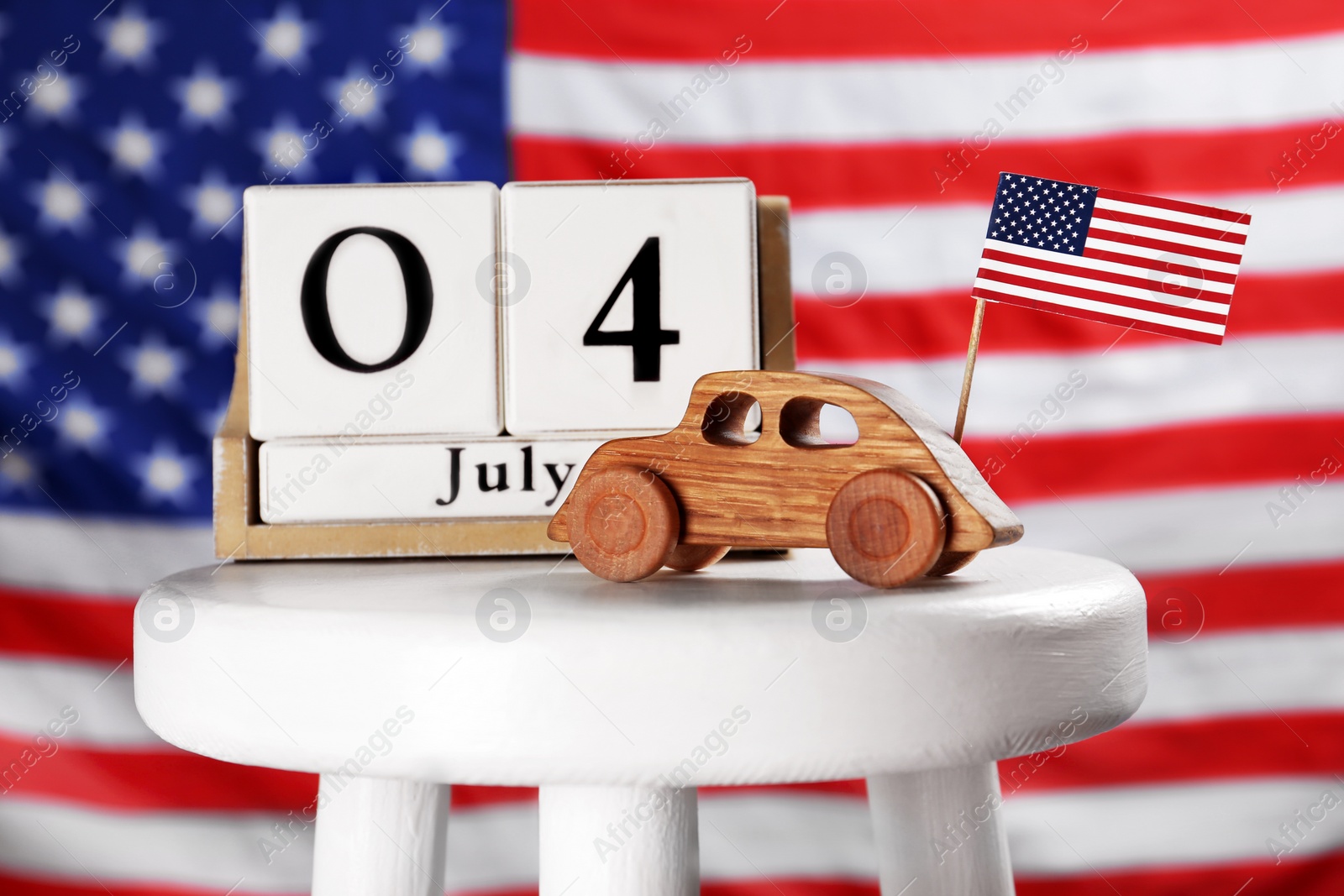 Photo of Composition with calendar and wooden car on stool against USA flag
