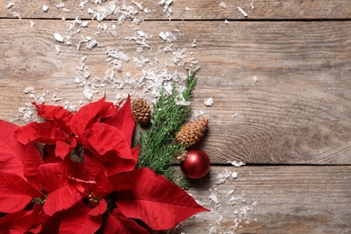 Photo of Flat lay composition with poinsettia and space for text on wooden background. Traditional Christmas flower