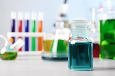 Photo of Glass reagent bottle and other glassware on table in chemistry laboratory. Space for text