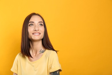 Portrait of pretty young woman with gorgeous chestnut hair and charming smile on yellow background, space for text