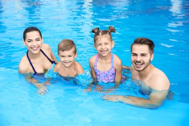 Photo of Young family with little children in swimming pool on sunny day