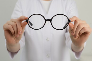 Woman with glasses on light background, closeup