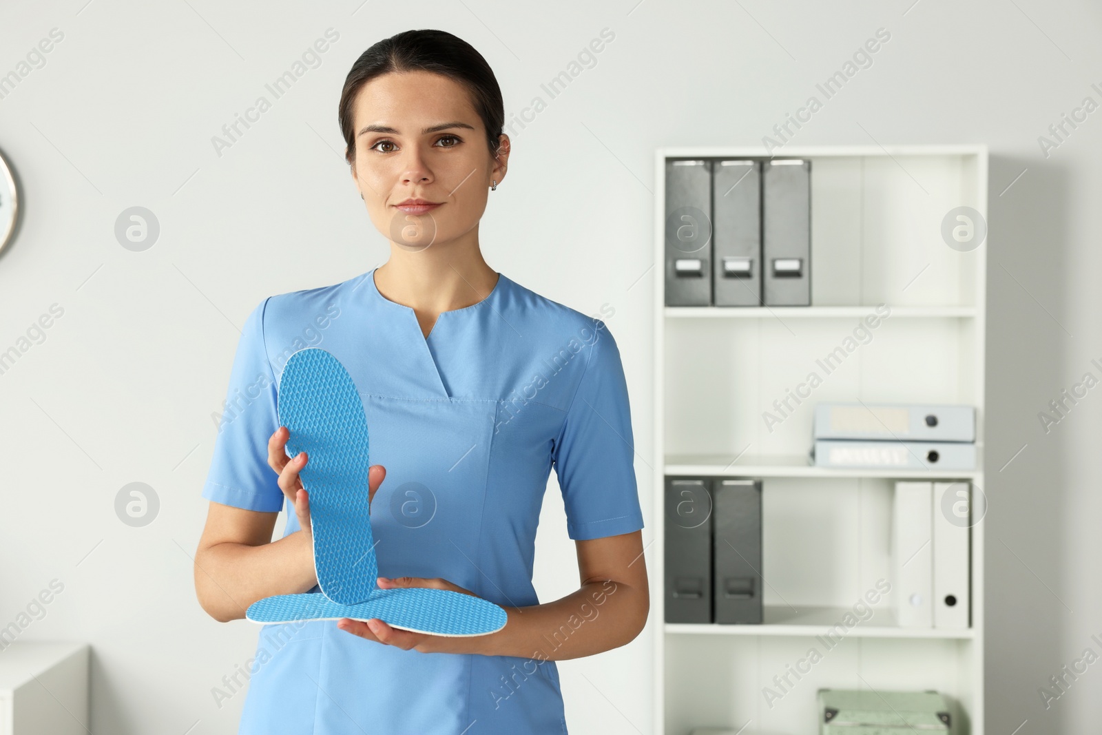 Photo of Beautiful female orthopedist showing insole in hospital