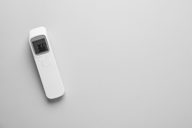Photo of Infrared thermometer on grey background, top view with space for text. Checking temperature during Covid-19 pandemic