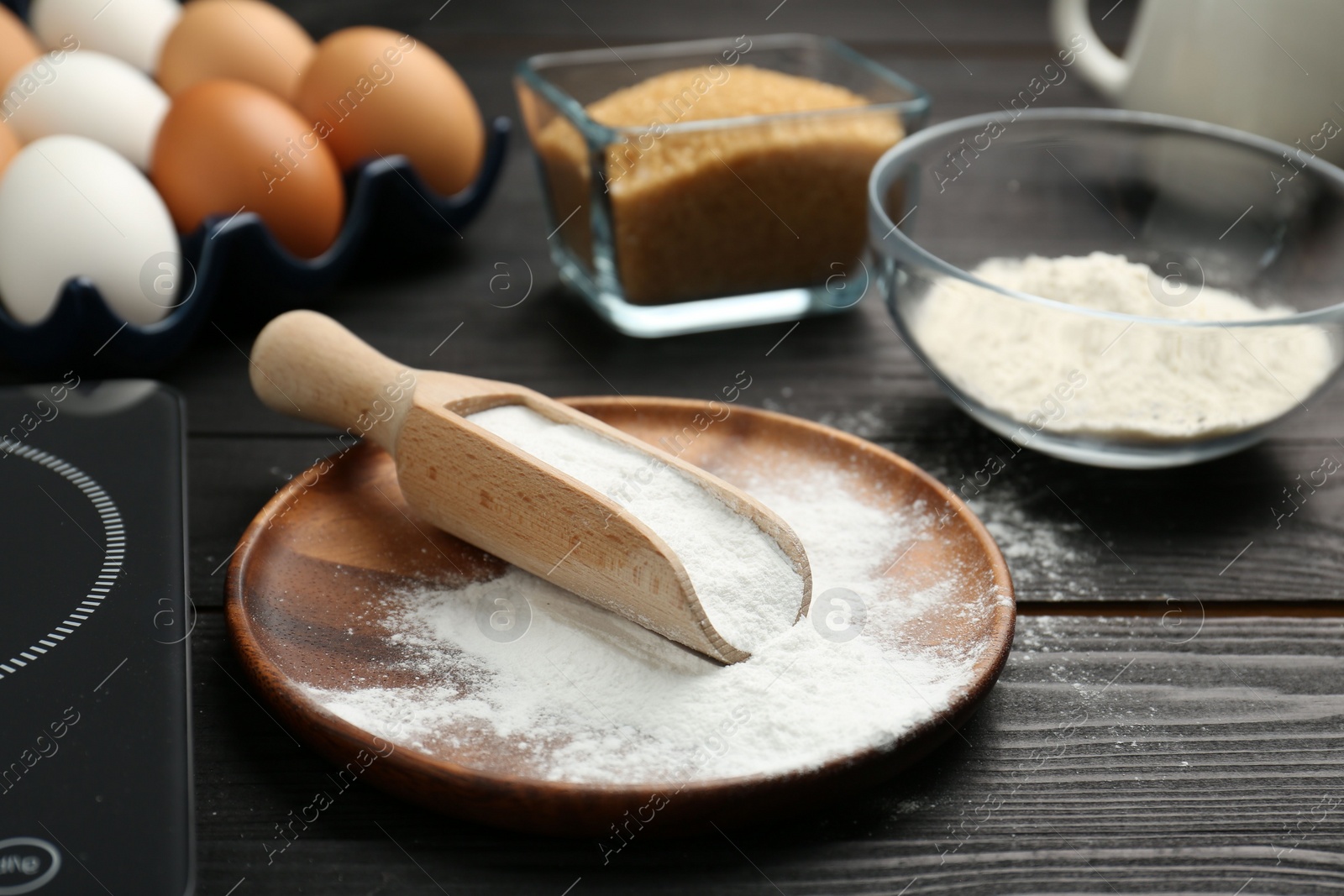 Photo of Baking powder and other products on black wooden table, closeup