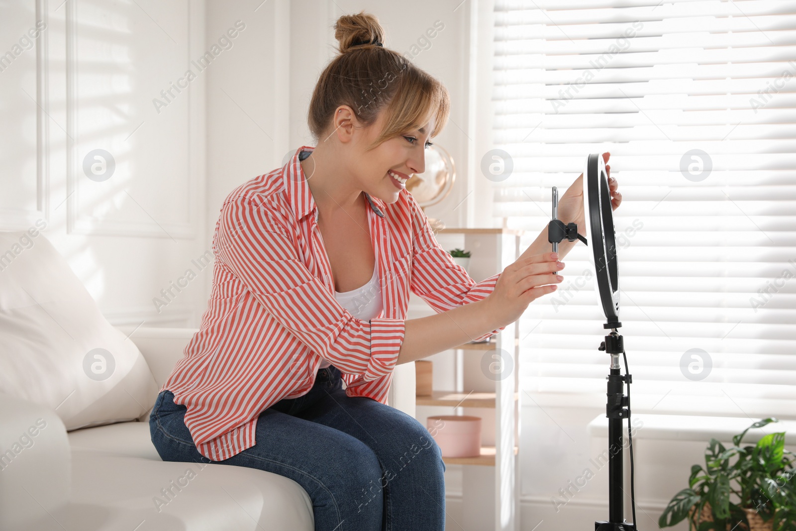 Photo of Blogger preparing for video recording at home. Using ring lamp and smartphone