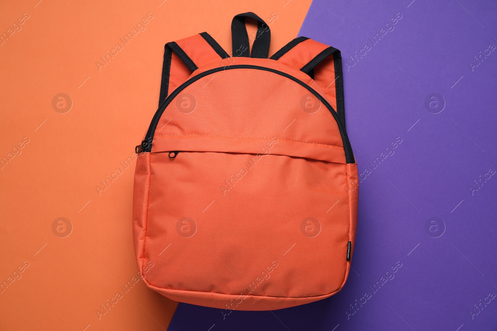 Photo of Stylish orange backpack on color background, top view