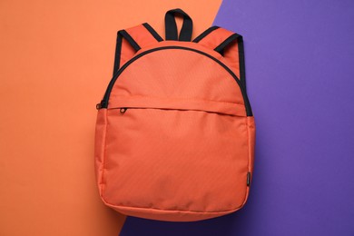 Stylish orange backpack on color background, top view