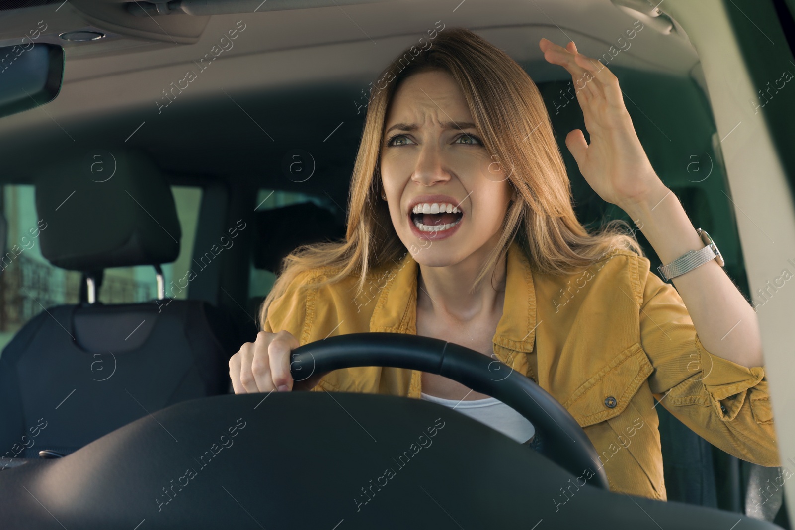 Photo of Stressed angry woman in driver's seat of modern car, view through windshield