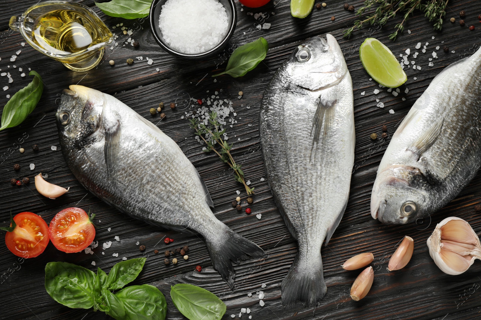 Photo of Flat lay composition with raw dorada fish on black wooden table