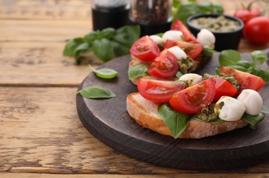 Delicious Caprese sandwiches with mozzarella, tomatoes, basil and pesto sauce on wooden table, closeup. Space for text